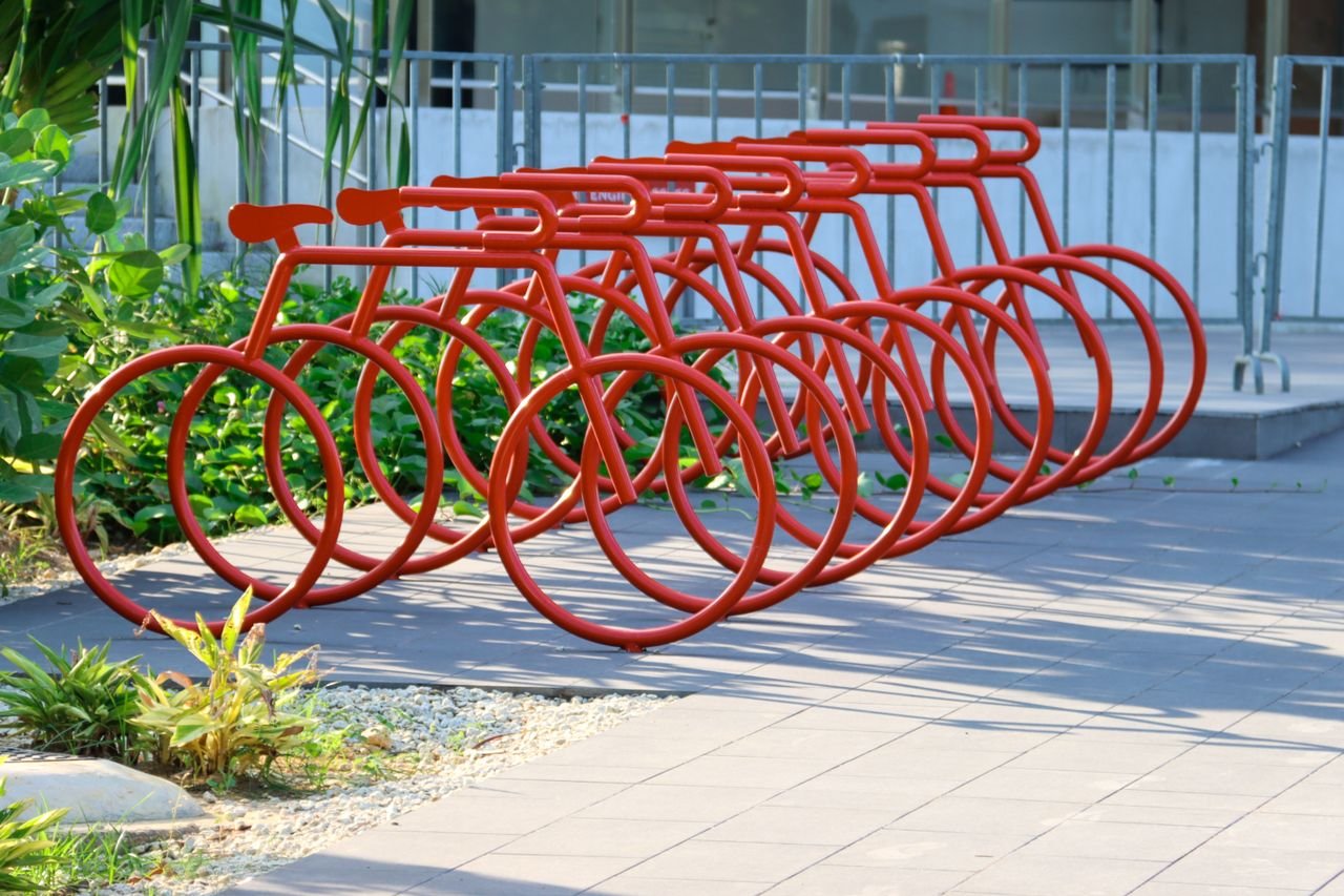 Artistic red bicycle-shaped rack in Singapore, blending urban design with greenery.