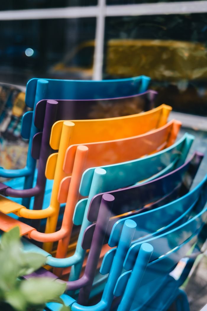 Vibrant, colorful chairs stacked outside a cafe creating a playful and modern scene.