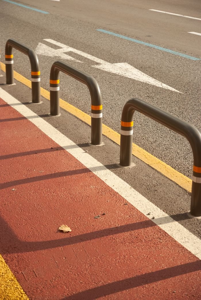City street with bike lane, barriers, and directional markings on a sunny day.